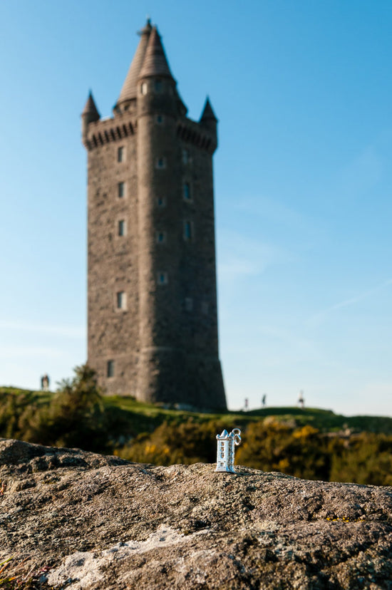 A photograph looking up at Scrabo Tower and in the foreground is NI Silver's silver Scrabo Tower necklace.