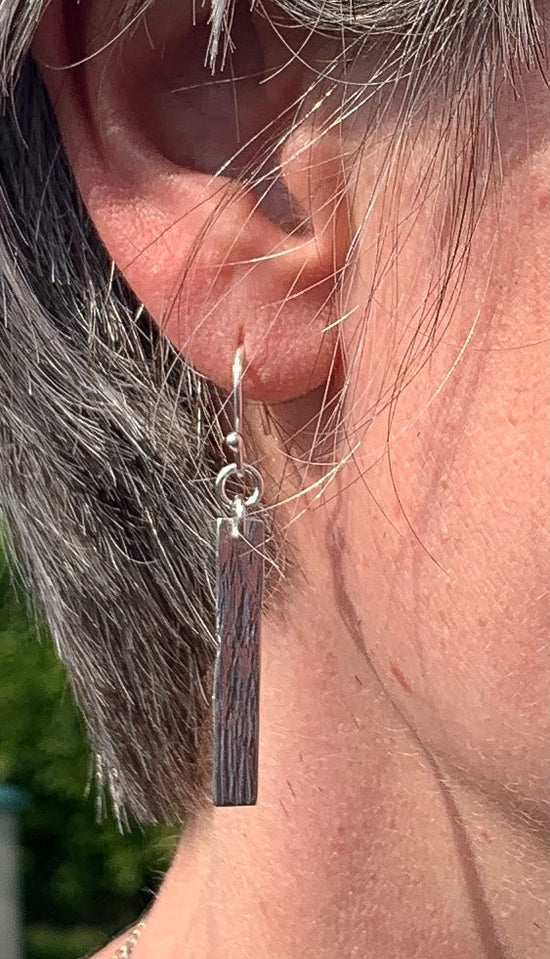 Lady wearing the silver rectangle earrings she made at a NI Silver Jewellery Making experience.