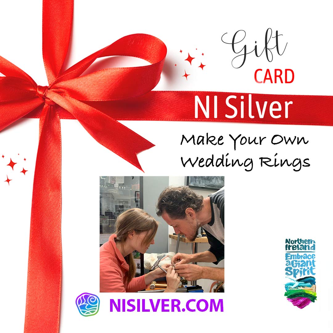 A gift card with a red bow and NI Silver's logo and Tourism NI's Embrace a Giant Spirit logo. Smaller picutre shows a couple bent close together looking at a bespoke handmade wedding ring that they are making for each other. Part of the NI Silver Jewellery Bespoke Make Your Own Wedding Ring experience in Northern Ireland.