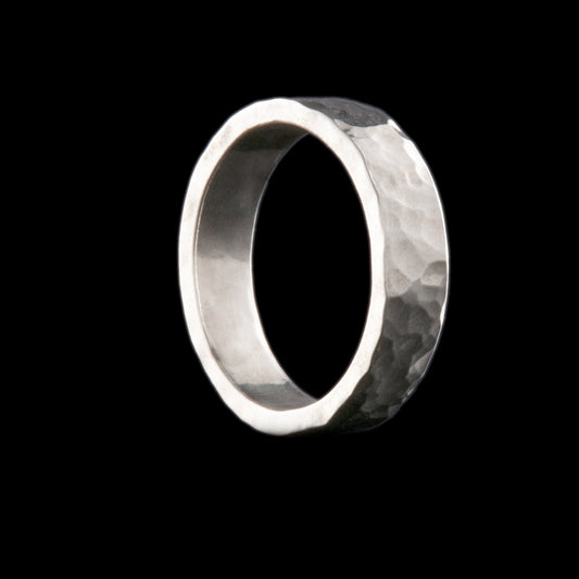 Silver ring inspired by the golf ball dimples, this ring has a textured surface, shown here aagainst a a black background.  5mm band of ring here.