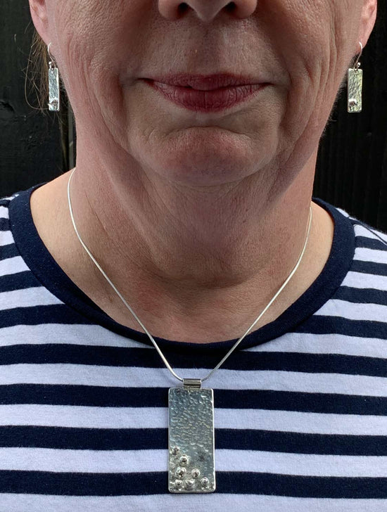 A lady wearing her handmade silver necklace and earrings made during a NI Silver jewellery making workshop