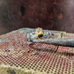 A silver ring with a gold plated crown and heart, resting on top of a rusty metal workbench surface.