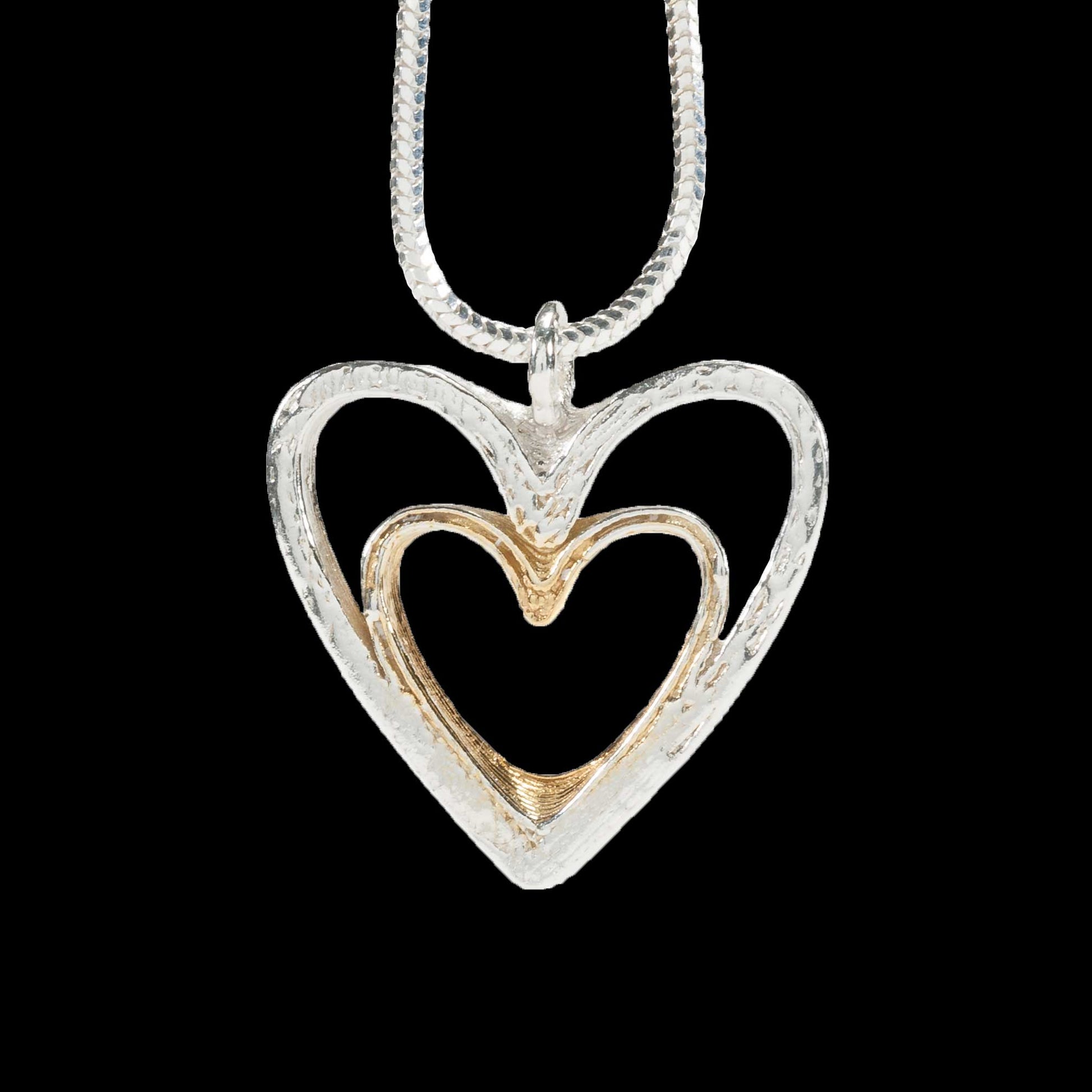 2 Slices of heart shape made out of silver, one fitting inside the other with the smaller gold plated.  On a silver chain.